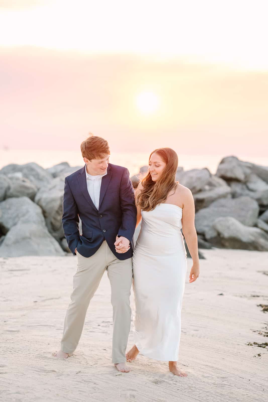 couple walks on the beach at sunset for engagement photos in Fairhope al