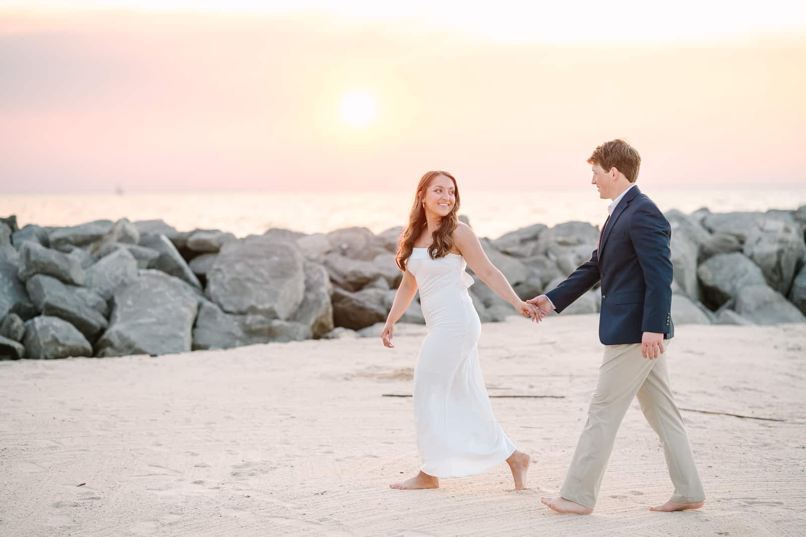 fiancé leads groom on walk on the beach at The Grand Hotel at Sunset