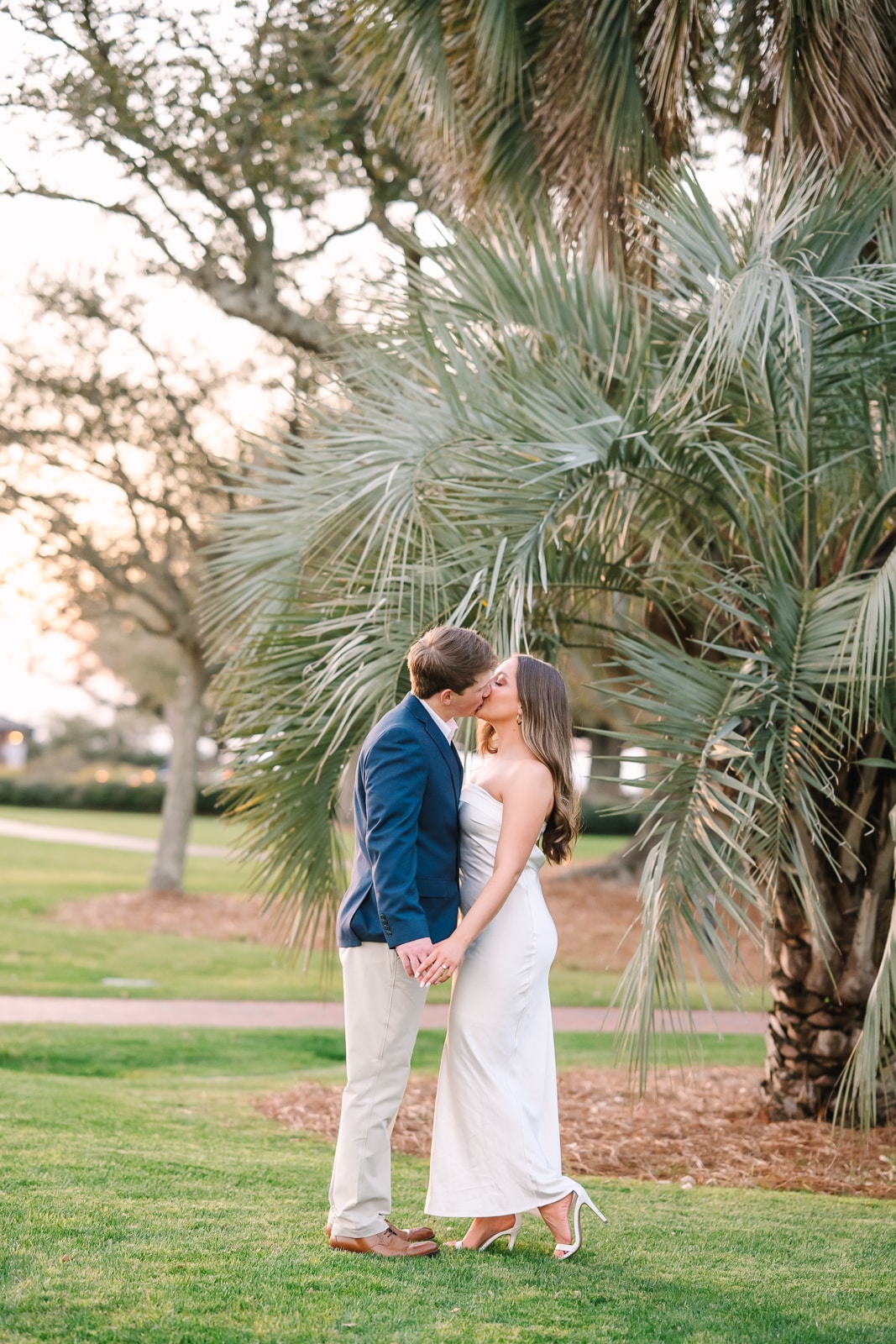 couple kisses in front of palm tree at sunset at The Grand Hotel