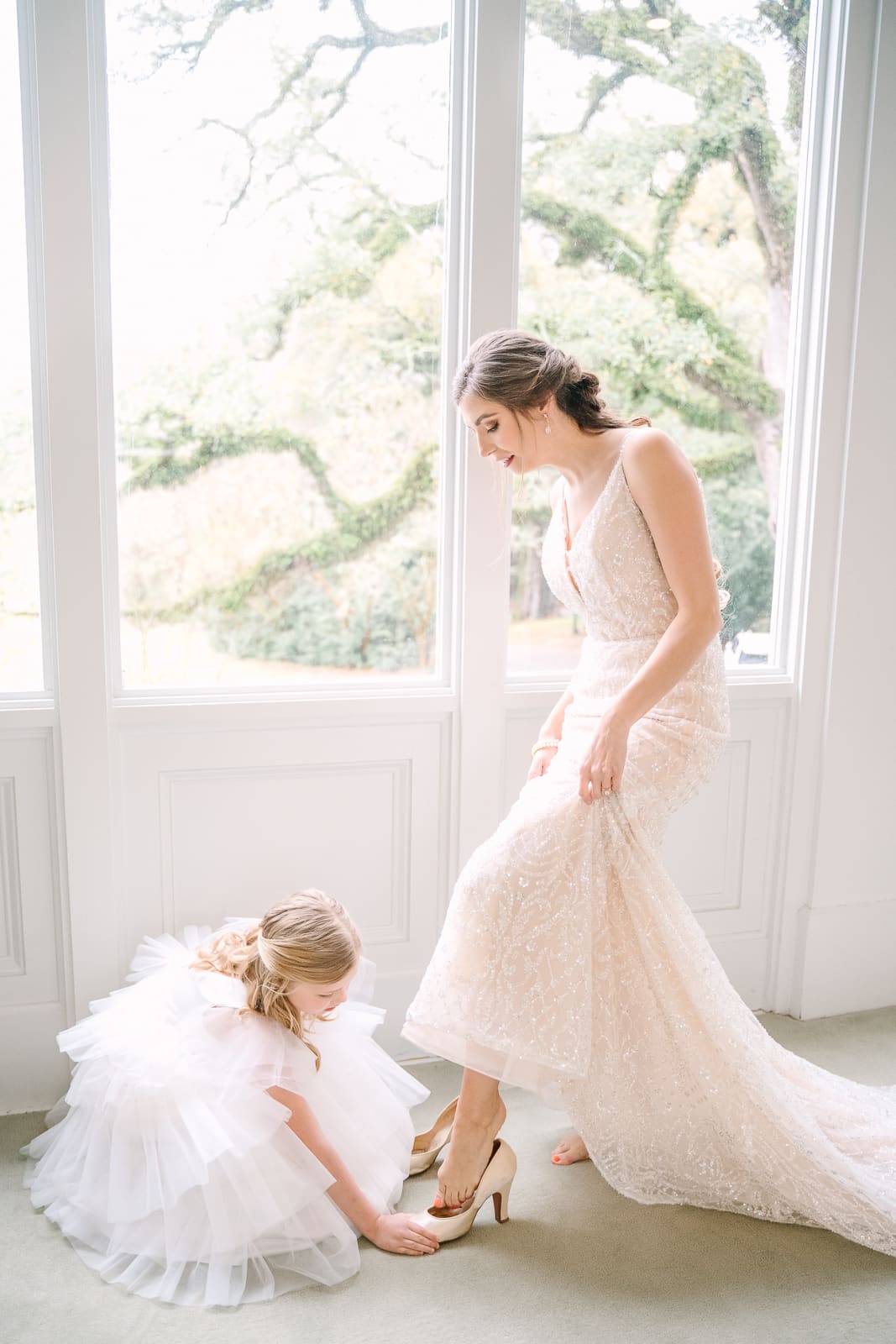 Flower girl putting brides shoes on her in Bridal room at Bragg Mitchell Mansion